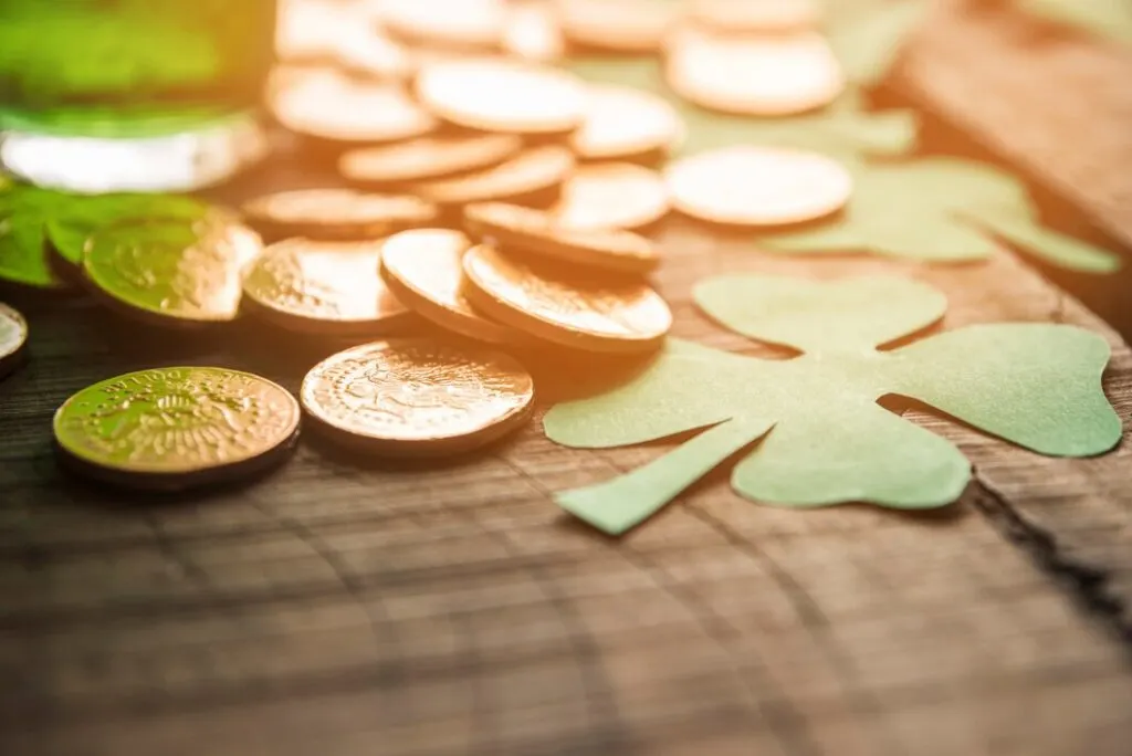 Coins and paper shamrocks on table