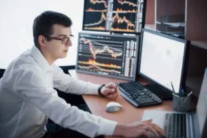 Stockbroker in shirt is working in a monitoring room with display screens.