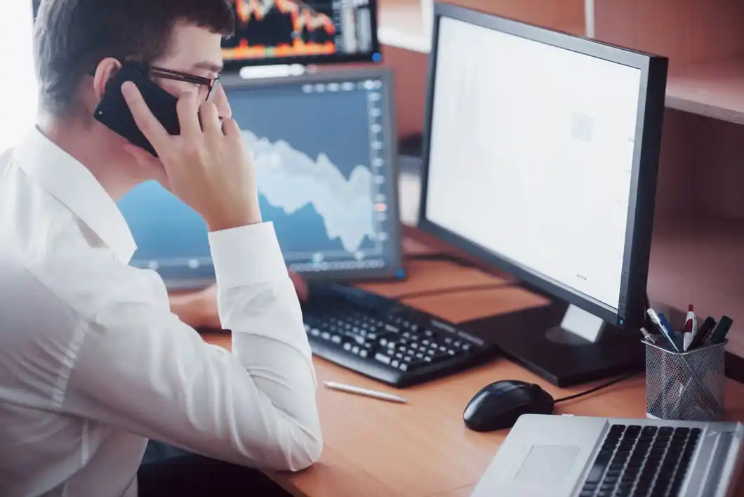 Stockbroker in shirt is working in a monitoring room with display screens