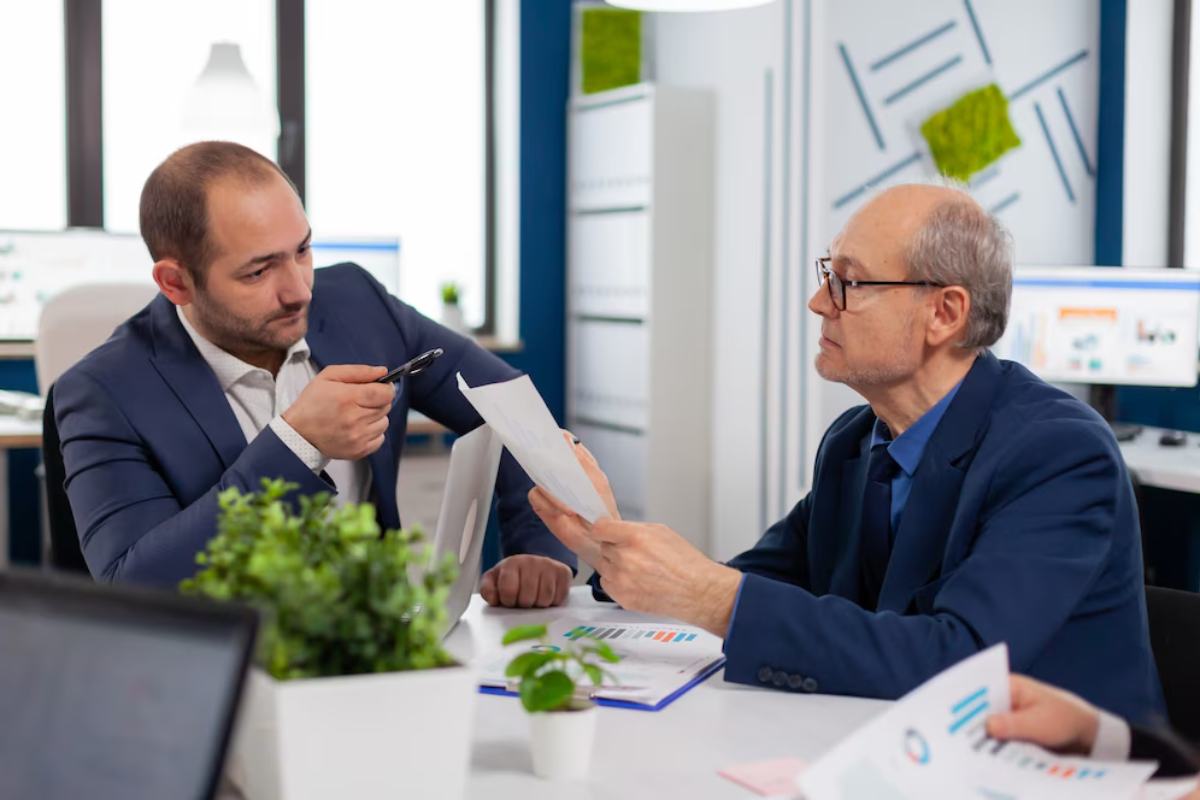Two men engage in a discussion over documents in a modern office
