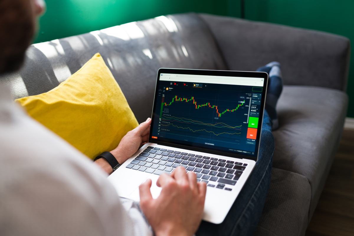 A man presents financial data on digital screens to a group of attentive colleagues in a meeting room.